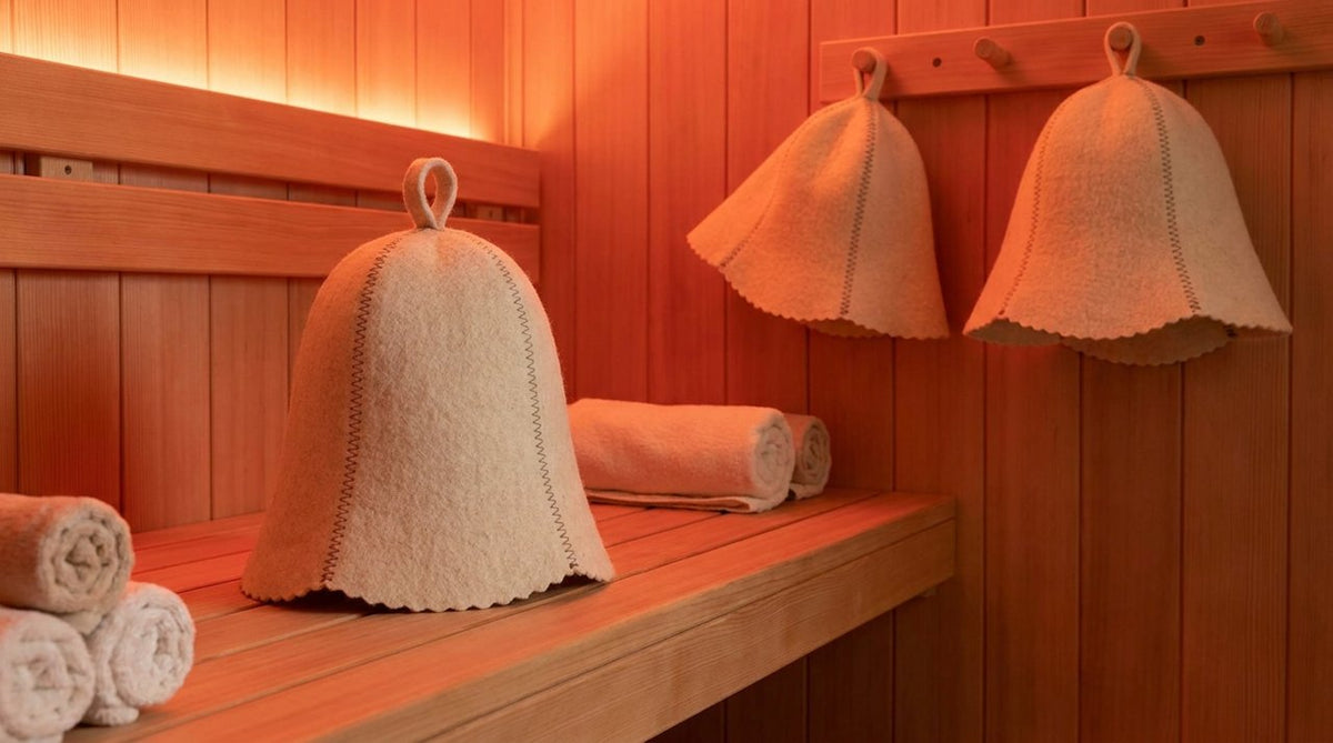 Modern infrared sauna cabin with warm red-orange glow, wooden interior, wool hat on bench